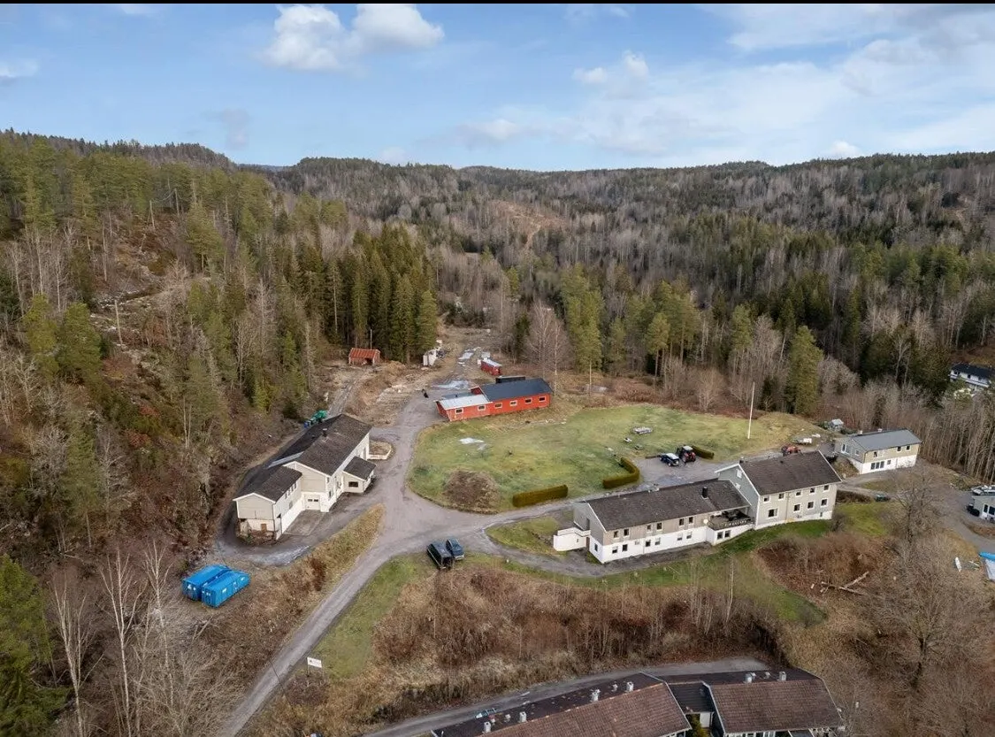 Kjønnerød gård med hvite bygninger, tun og jorder, sett fra lufta